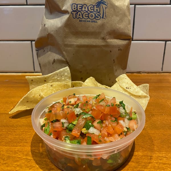 Pico de gallo and tortilla chips in front of a Beach Tacos takeout bag.