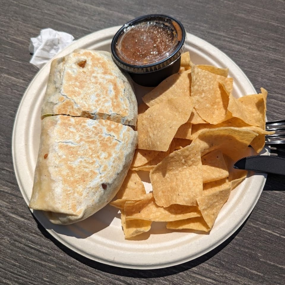 A Beach Tacos burrito, tortilla chips, and salsa on a white plate.